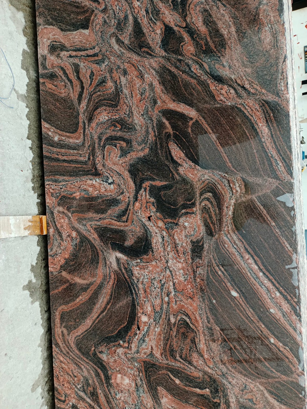 Polished granite slab with dark and terracotta veining